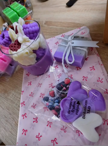 Pedido personalizado — vela morada, jabón y wax melts de frutos rojos sobre papel de lazos.